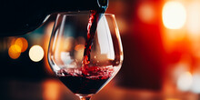 Pouring Red Wine Into A Glass While Celebrating Dinner Against A Bokeh Background