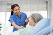 © SKW - A female nurse or doctor is caring for an elderly female patient lying on the patient's bed doing heart and breathing tests. and the patient has a smile
