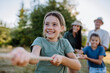 © Halfpoint - Young family with happy kids having fun together outdoors pulling rope in summer nature.