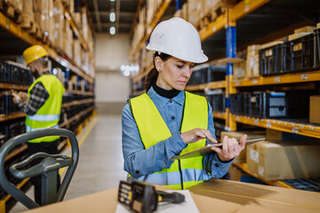 Warehouse workers checking stuff in warehouse with digital system in tablet, holding solar panel.