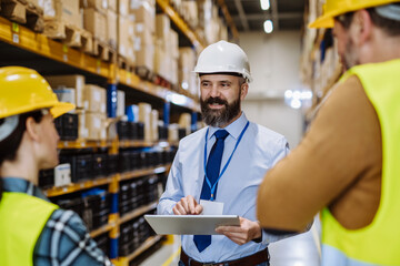 Wall Mural - Manager explaining work to his employers in warehouse.