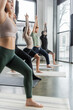 Multiethnic people practicing Crescent Lunge pose on yoga mats in studio.