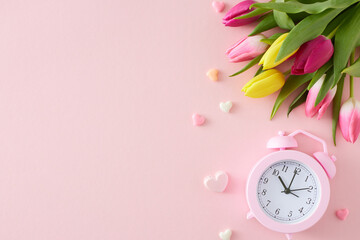 Wall Mural - Mother's Day mood concept. Flat lay photo of bouquet yellow pink tulips alarm clock and colorful hearts on pastel pink background with empty space