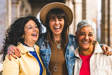 Multiracial Senior Women Having Fun Together Outdoor At City Street- Three Happy Mature Trendy Female Friends Hugging And Laughing On Urban Place- Friendship Lifestyle Concept With Elderly People 