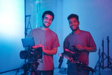 Wall Mural - Portrait of young operators smiling at camera while shooting video and photo content in studio