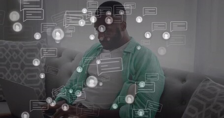 Animation of message and profile icons, african american man sitting on sofa and working on computer