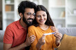 © Prostock-studio - Happy Young Indian Couple Looking At Positive Pregnancy Test At Home