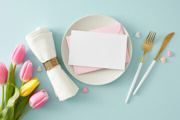 Mother's Day celebration concept. Top view photo of circle plate with white card cutlery knife fork fabric napkin colorful hearts and bouquet of flowers yellow pink tulips on pastel blue background