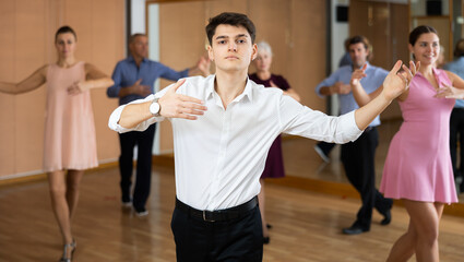 Poster - Interested young guy practicing movements of slow elegant wedding dance during group class in choreography studio