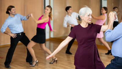 Wall Mural - elderly couple in their free time is engaged in latin dance class and learns movements of cha-cha-cha dance