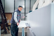 © Zamrznuti tonovi - A worker is cutting a wooden panel on a cutting machine at the workshop.
