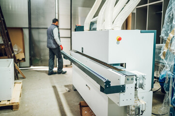 A machine for making furniture with the worker in the background.