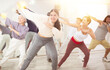 © JackF - Happy young woman practising modern dance moves with other people in dance studio
