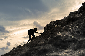Man climbing up mountain cliff edge. Sport challenge concept 