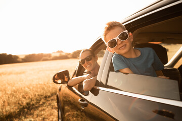 Wall Mural - Family road trip. Happy mother and little boy in the car. Family road trip, summer holiday travel. 