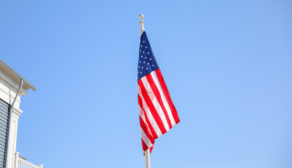 Wall Mural - The US flag on a pole is a symbol of patriotism and unity, representing the country's values, history, and people. Its design and colors have symbolic meaning