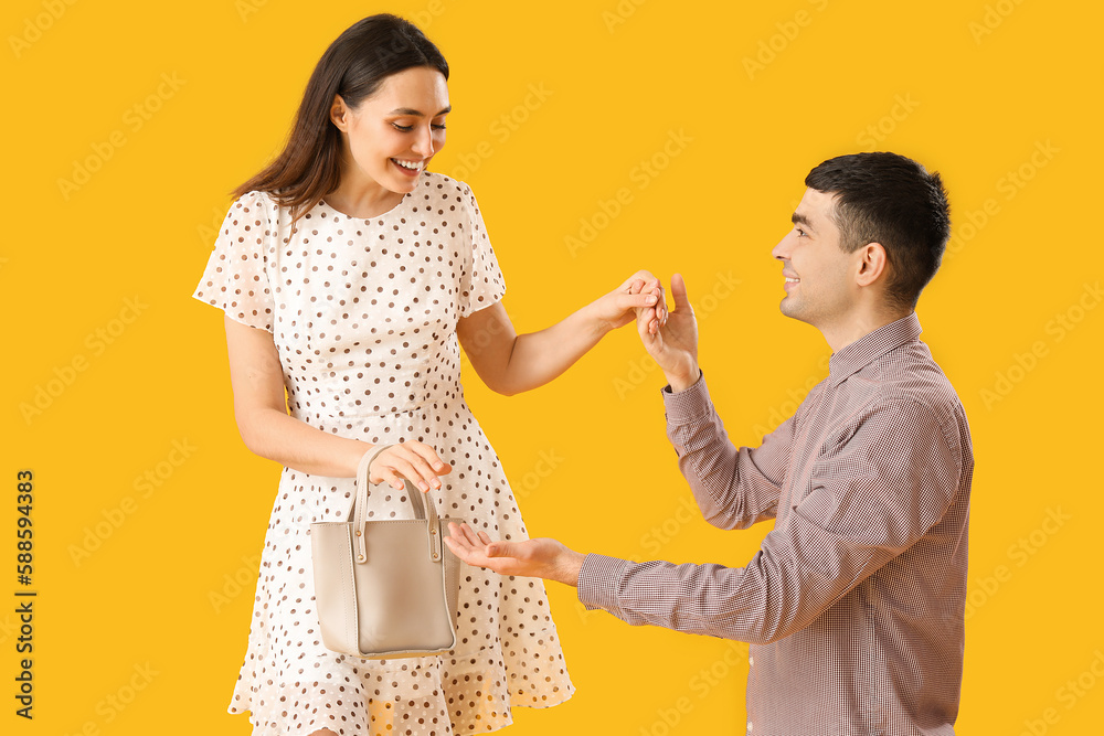 Lovely young couple holding hands on yellow background