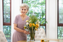 Happy Senior Chinese Woman Arranging Flowers At Home