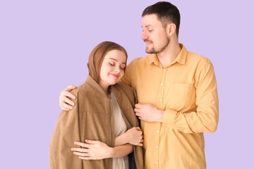 Sticker - Young man hugging wife in his jacket on lilac background