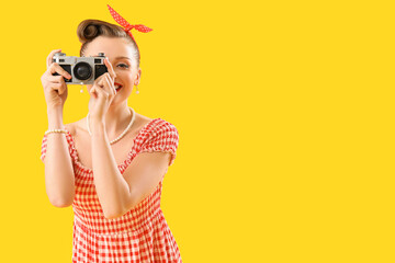 Poster - Young pin-up woman with photo camera on yellow background