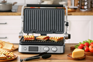 Modern electric grill with delicious sandwiches on kitchen counter