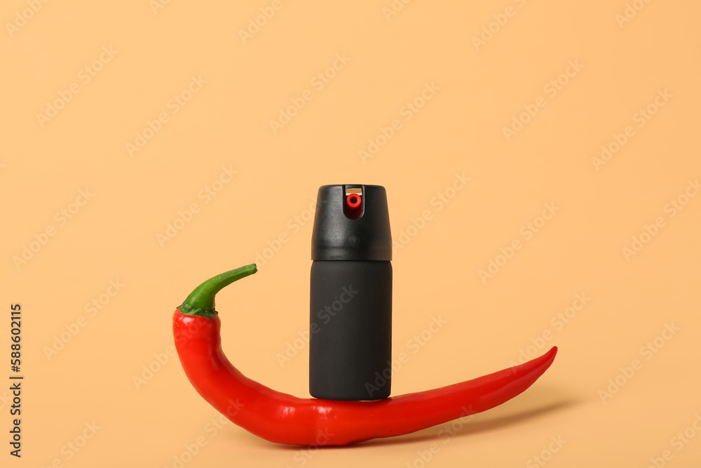 Spray with chili pepper on beige background