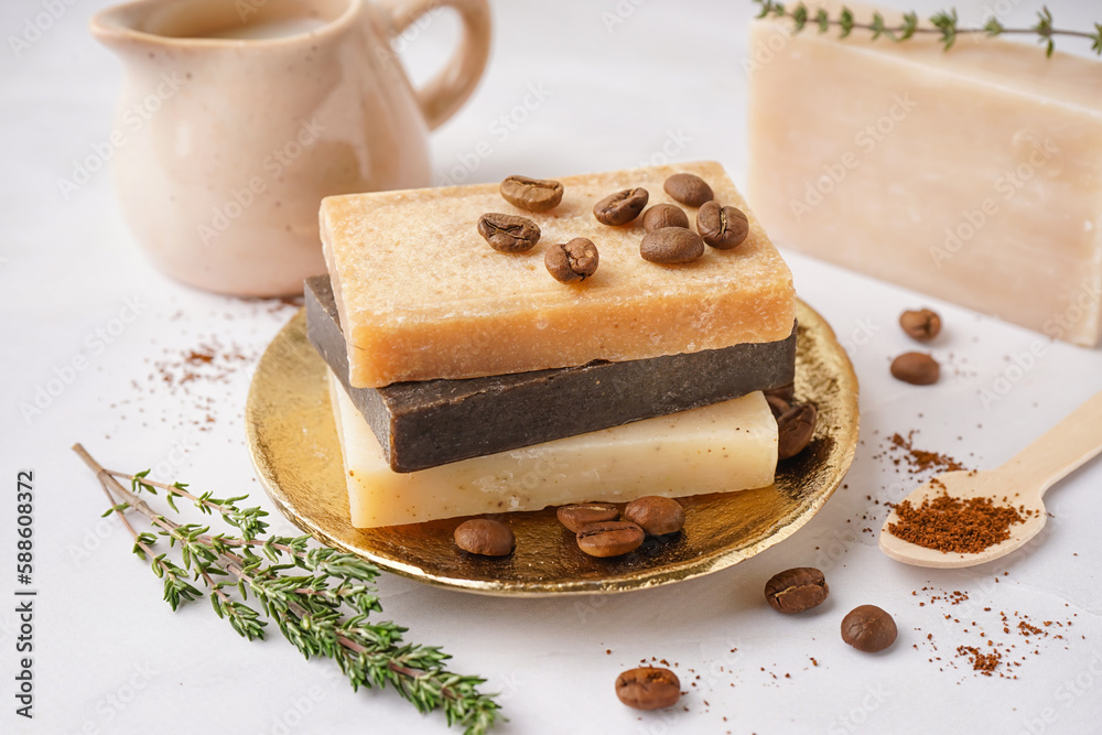 Plate with natural soap bars, coffee beans and thyme on light table