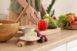 © Pixel-Shot - Mature woman making vegetable salad at table in kitchen, closeup