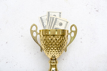 Gold cup with money on light background