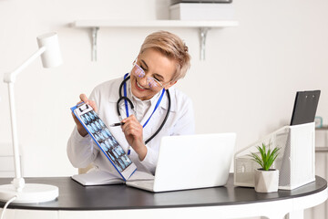 Canvas Print - Mature female doctor video chatting with patient. Concept of telemedicine