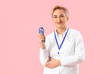 Canvas Print - Mature female doctor with stethoscope on pink background