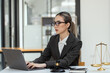 © SOMKID - Asian lawyer woman working at law office desk, law firms, advice and justice concept.