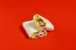 Chicken shawarma with white sauce on a red background in minimalist style. Bold red backdrop, hard shadows, modern food photography. Tasty wrap, burrito, tortilla, convenient meal, horizontal frame