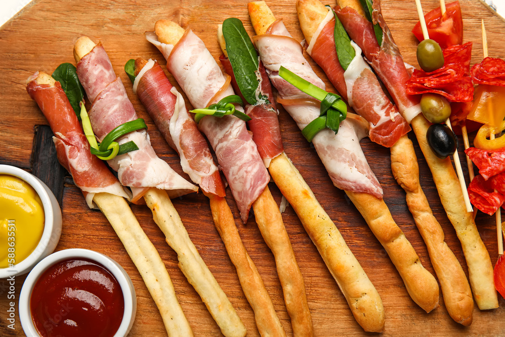 Tasty Italian Grissini with bacon on table, closeup