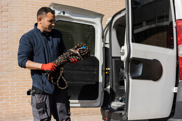 Hispanic male craftsman electrician taking tools out of his professional van - solar panel installation