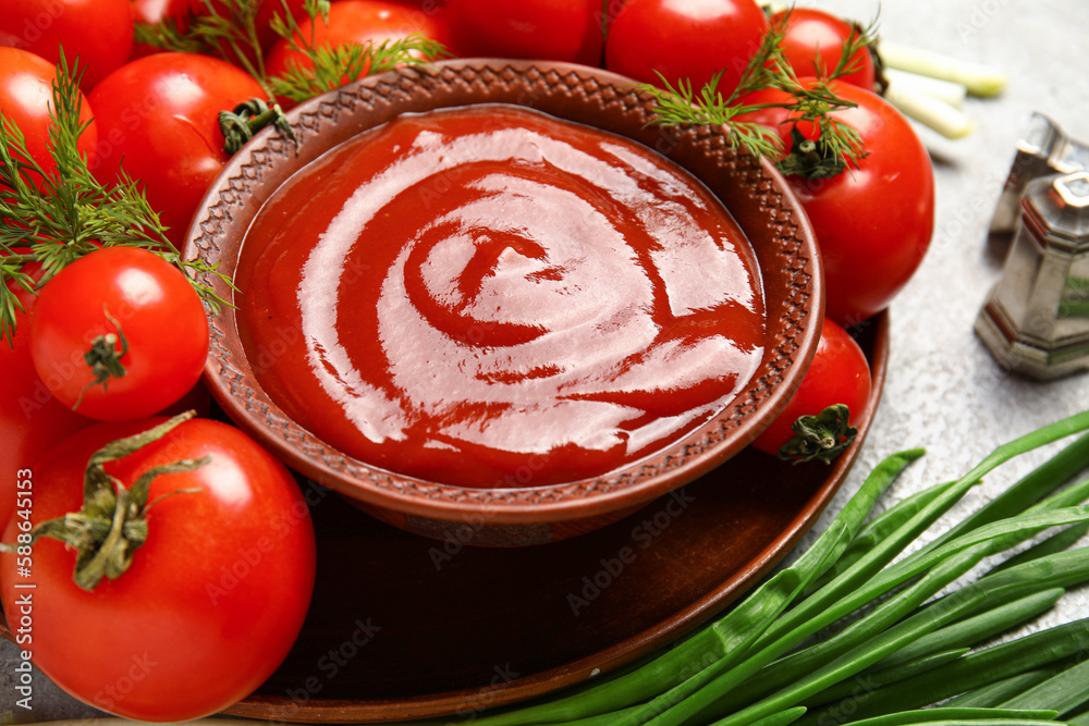 Bowl with tasty ketchup and fresh vegetables on table, closeup