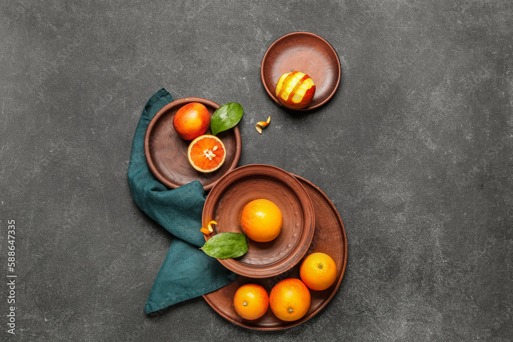 Plates with tasty blood oranges on dark background