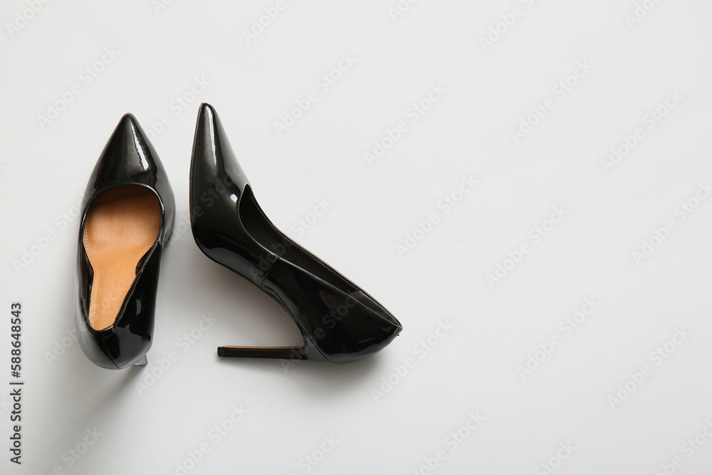 Pair of black high heeled shoes on light background