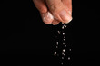© yaroslav1986 - Female fingers sprinkle salt on a black background, copy the space. Macrophotography