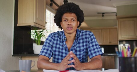 Wall Mural - serious african american man gesturing on video call in kitchen