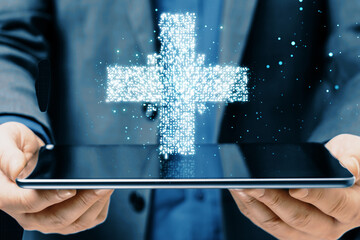 Aufkleber - Close up of businessman hand holding tablet with creative glowing medical cross plus hologram on dark background. Healthcare and digital transformation concept.