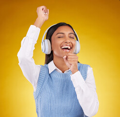 Poster - Headphones, energy and female singing in studio while listening to music, playlist or album. Happy, smile and Indian woman model doing karaoke while streaming a song isolated by yellow background.