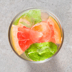 Wall Mural - Refreshing grapefruit drink with mint leaves and ice on gray stone table