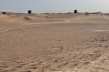 scenic view of desert against sky under the clear blue sky with the sun shining bright