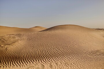 scenic view of desert against sky under the clear blue sky with the sun shining bright
