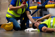 © NVB Stocker - First Aid. Engineering supervisor helping to give first aid to head injured foreman  lying unconscious at industrial factory. Professional engineering teamwork concept.