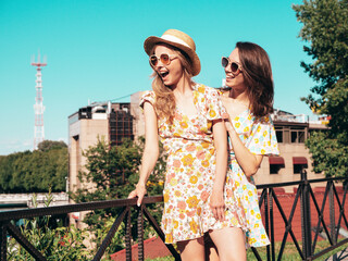 Wall Mural - Two young beautiful smiling hipster female in trendy summer dresses clothes. Sexy carefree women posing in the street. Positive models having fun, talking, chatting. Going crazy