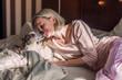 © Tatyana Gladskih - Happy middle aged woman sits on bed and stretching arms