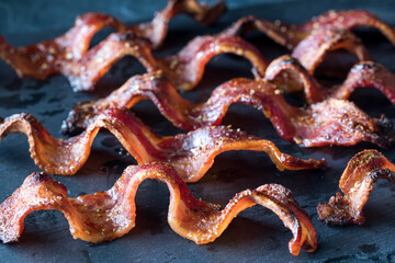 Wall Mural - strips of crispy maple pepper bacon on a black slate board.