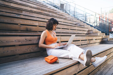 Wall Mural - Focused woman working on laptop at street